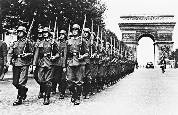 Fotografía histórica de tropas desfilando bajo el Arco del Triunfo durante la Segunda Guerra Mundial