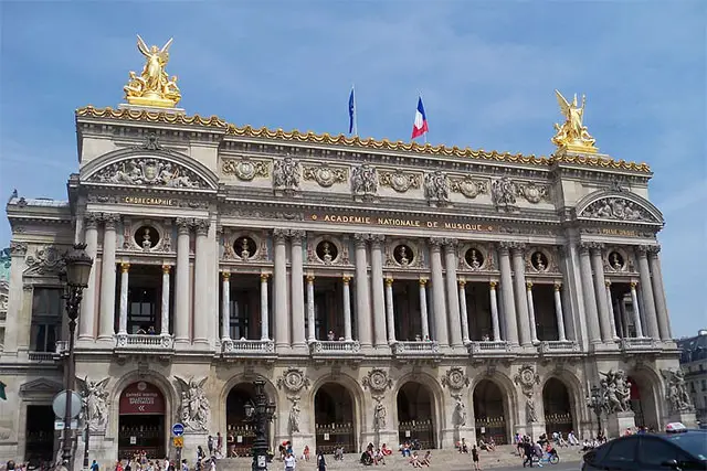 Vista panorámica de la fachada principal de la Ópera Garnier iluminada al atardecer en París