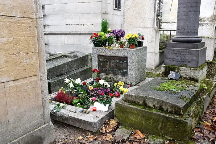 Tumba de Jim Morrison en el cementerio Père-Lachaise de París, cubierta de flores y mensajes de fans